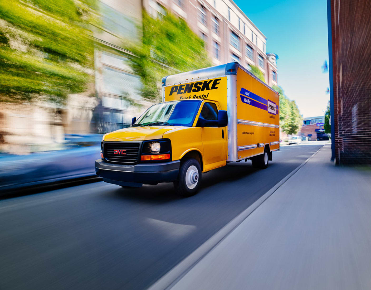 A yellow Penske van driving down a residential street.